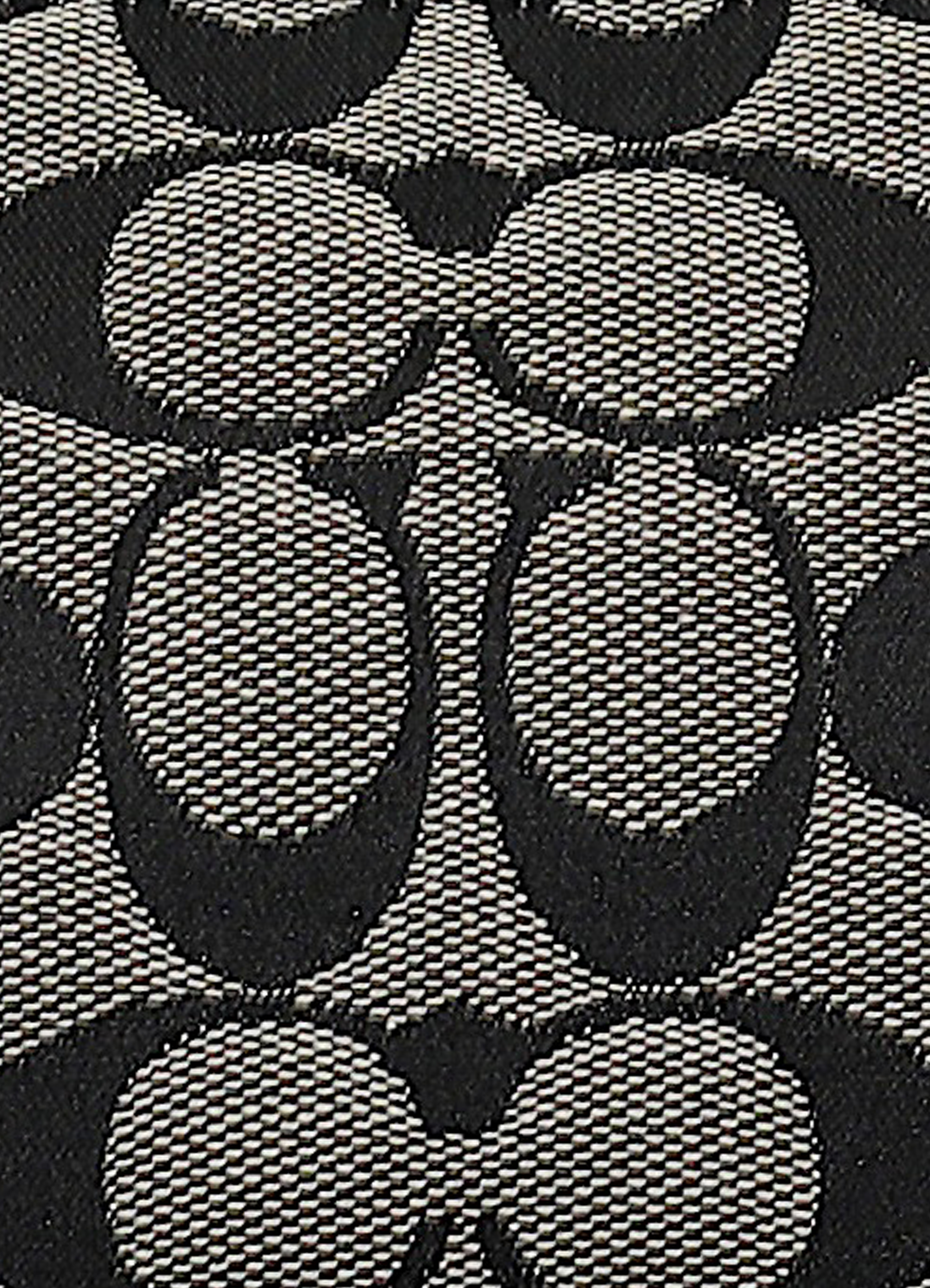 Macro shot of authentic black and grey Coach signature "C" jacquard canvas