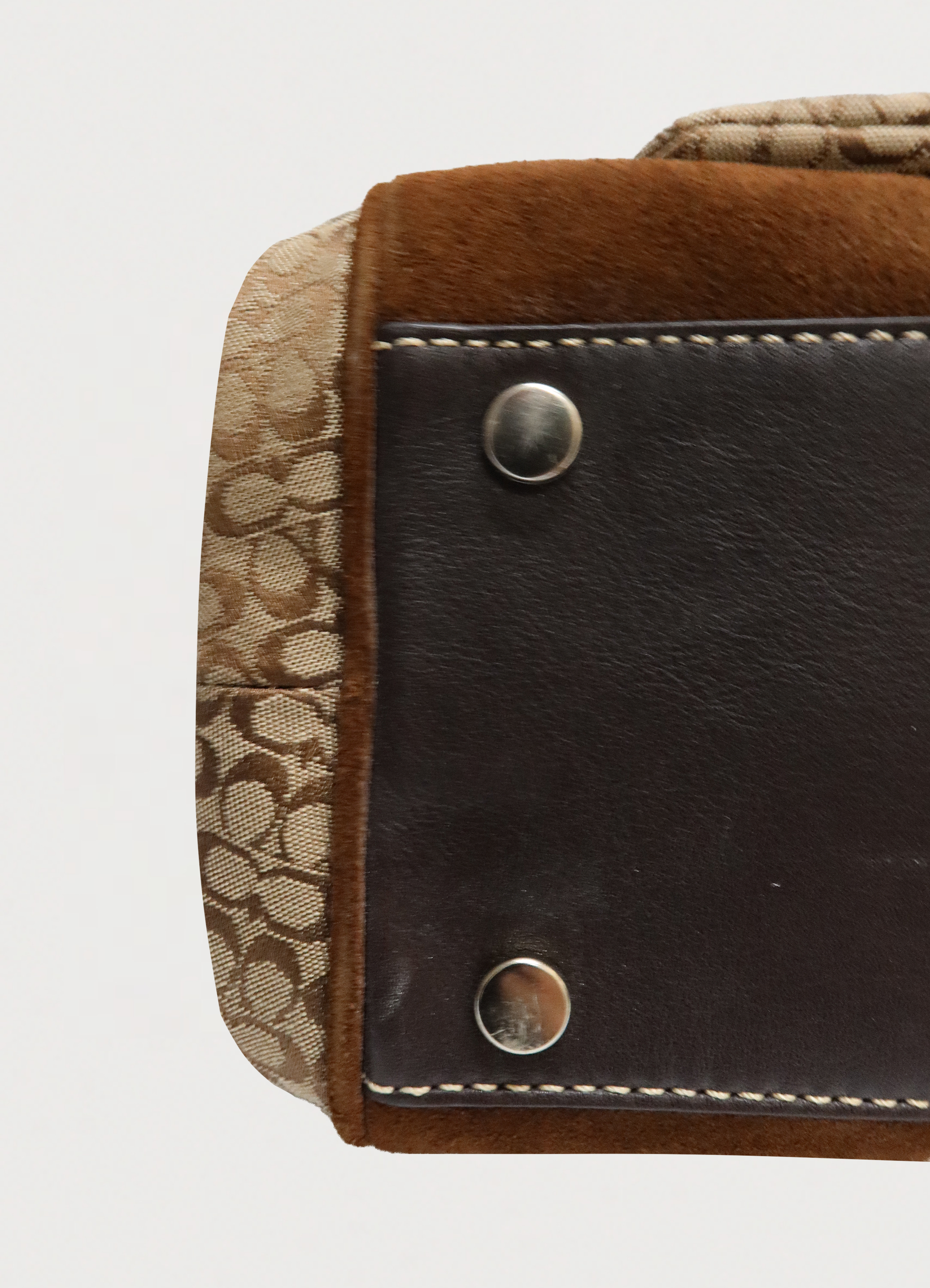 Close up of brown suede corner trim and brass protective feet on Coach satchel