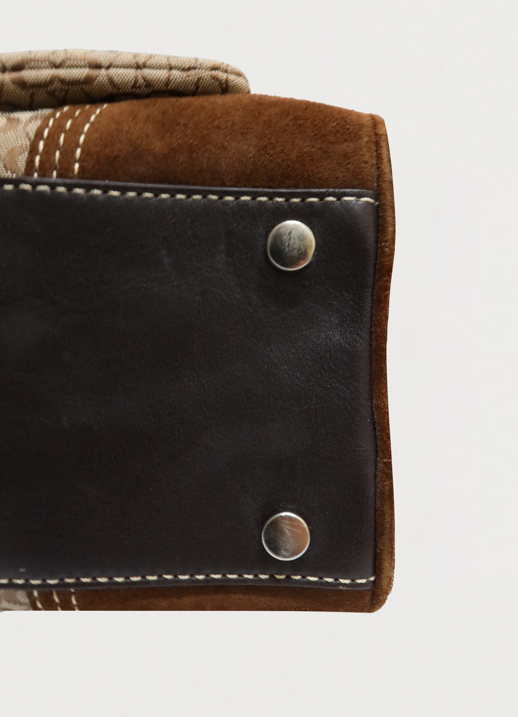 Close up of brown suede corner trim and brass protective feet on Coach satchel