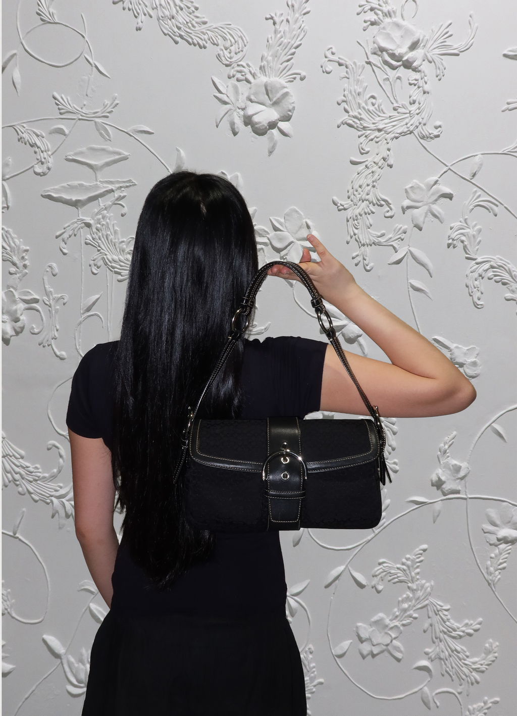 Black Coach Soho monogram flap bag held by model
