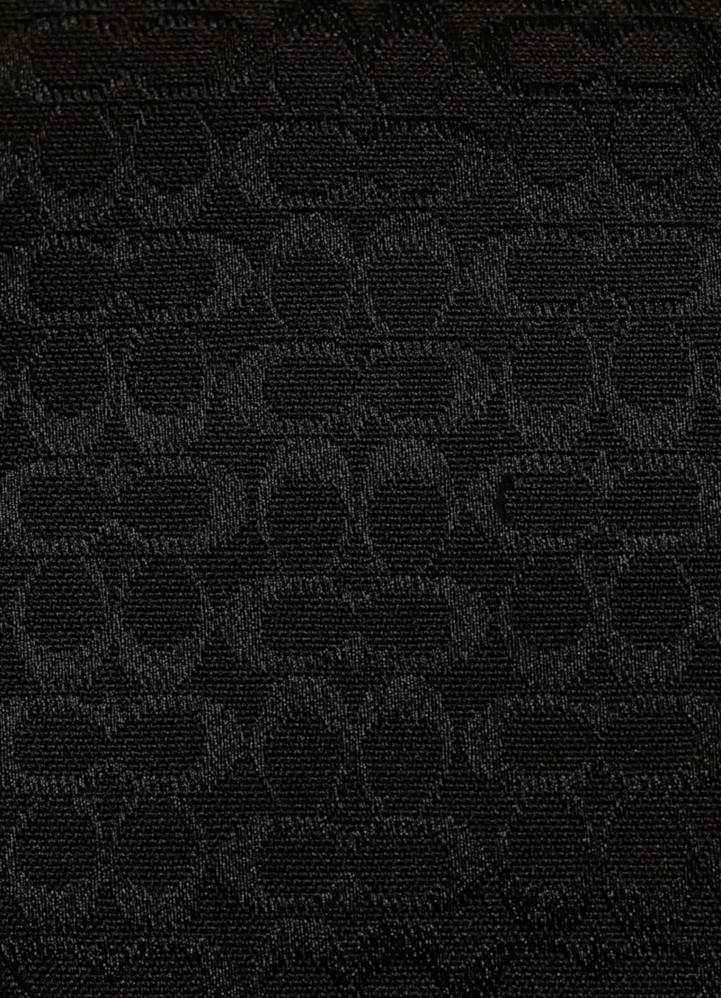 Macro shot of authentic black-on-black Coach signature jacquard canvas
