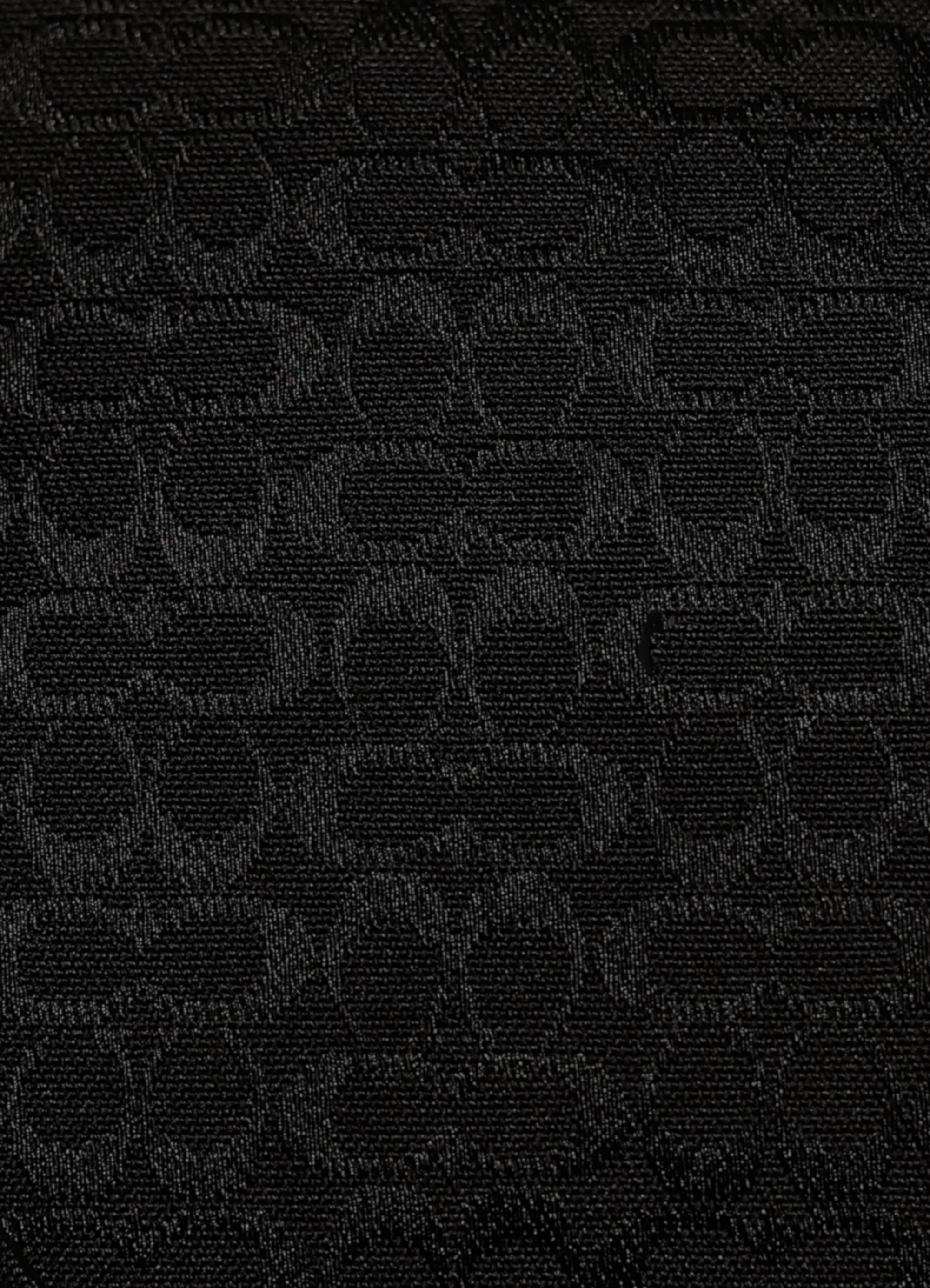 Macro shot of authentic black-on-black Coach signature jacquard canvas