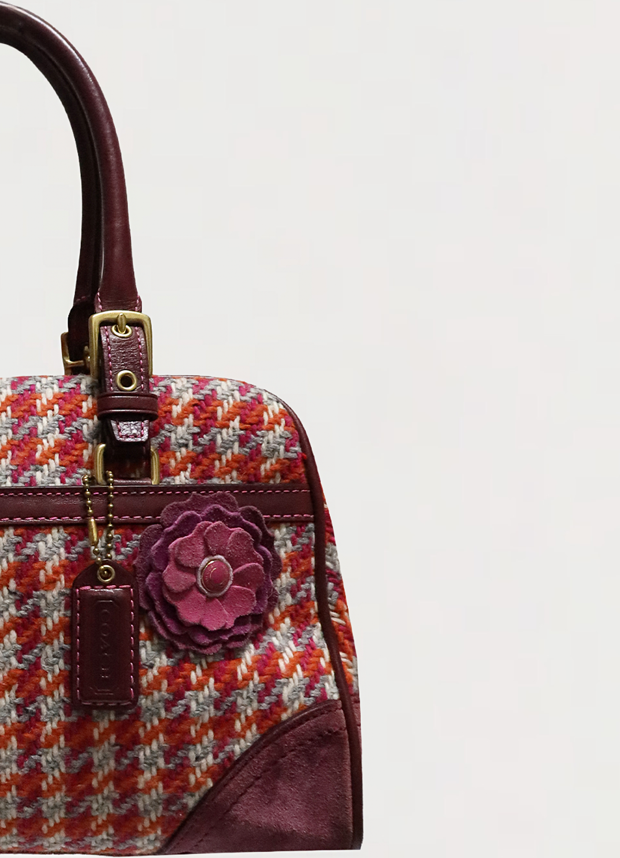Close up of the leather flower charm and brass hardware on the Coach Hadley satchel