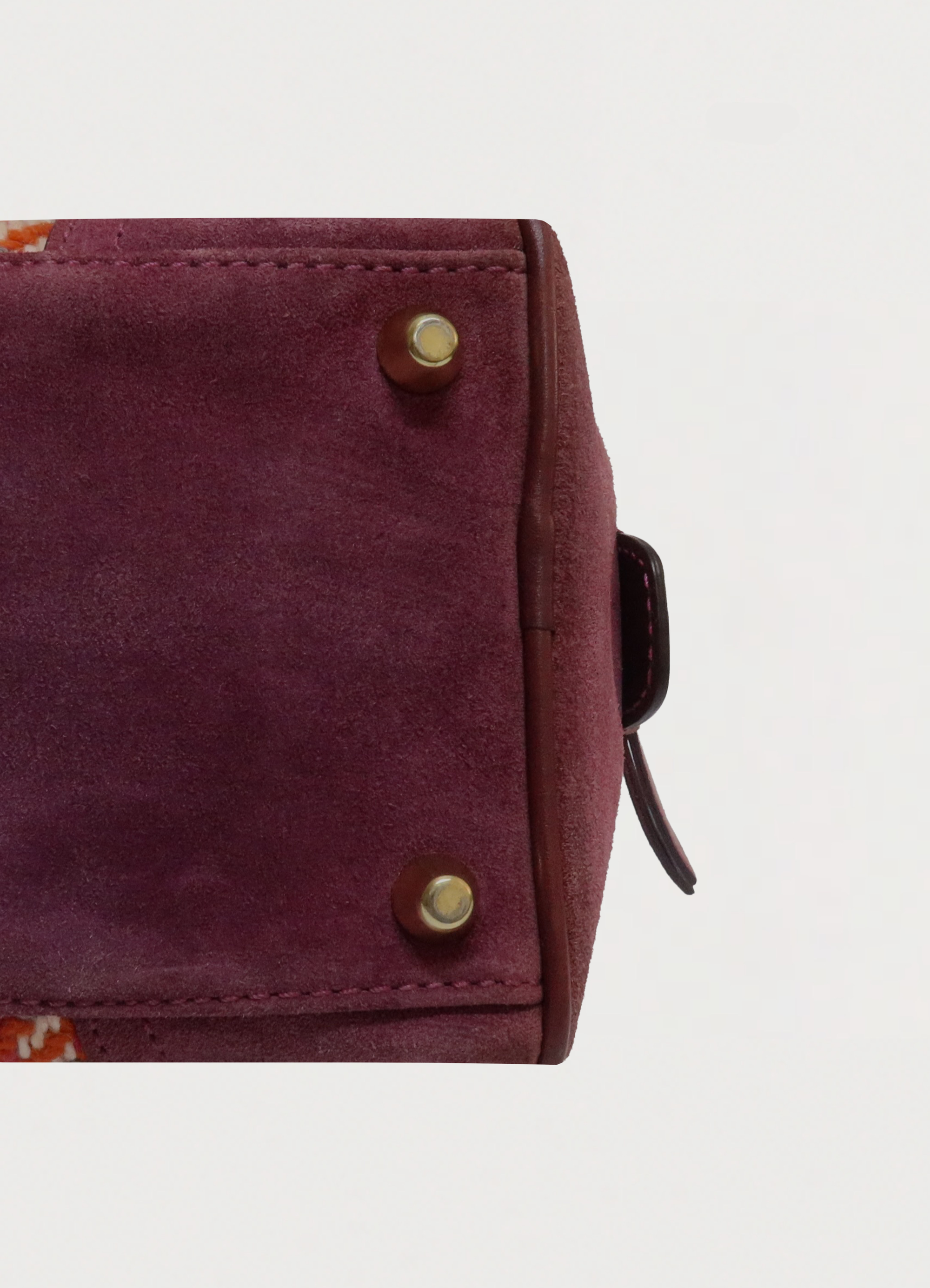 Detailed shot of suede trim and stitching on the base of the Coach Hadley bag