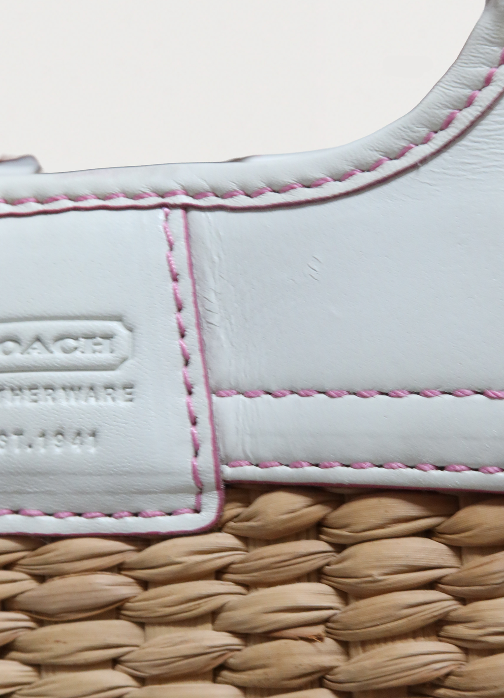 Close up of embossed Coach logo on the white leather trim detail
