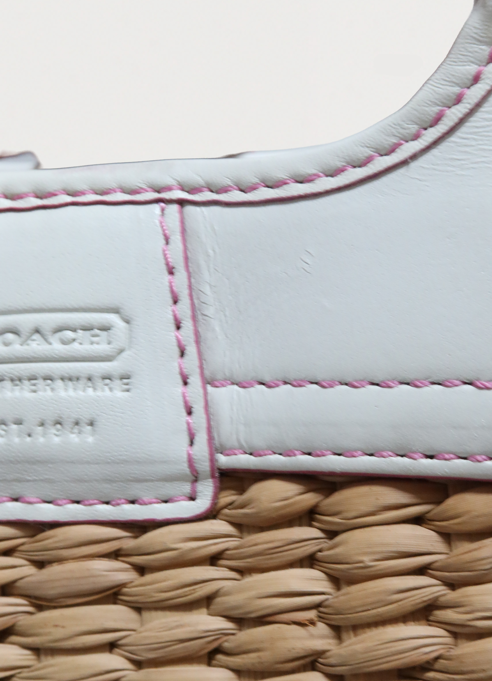 Close up of embossed Coach logo on the white leather trim detail