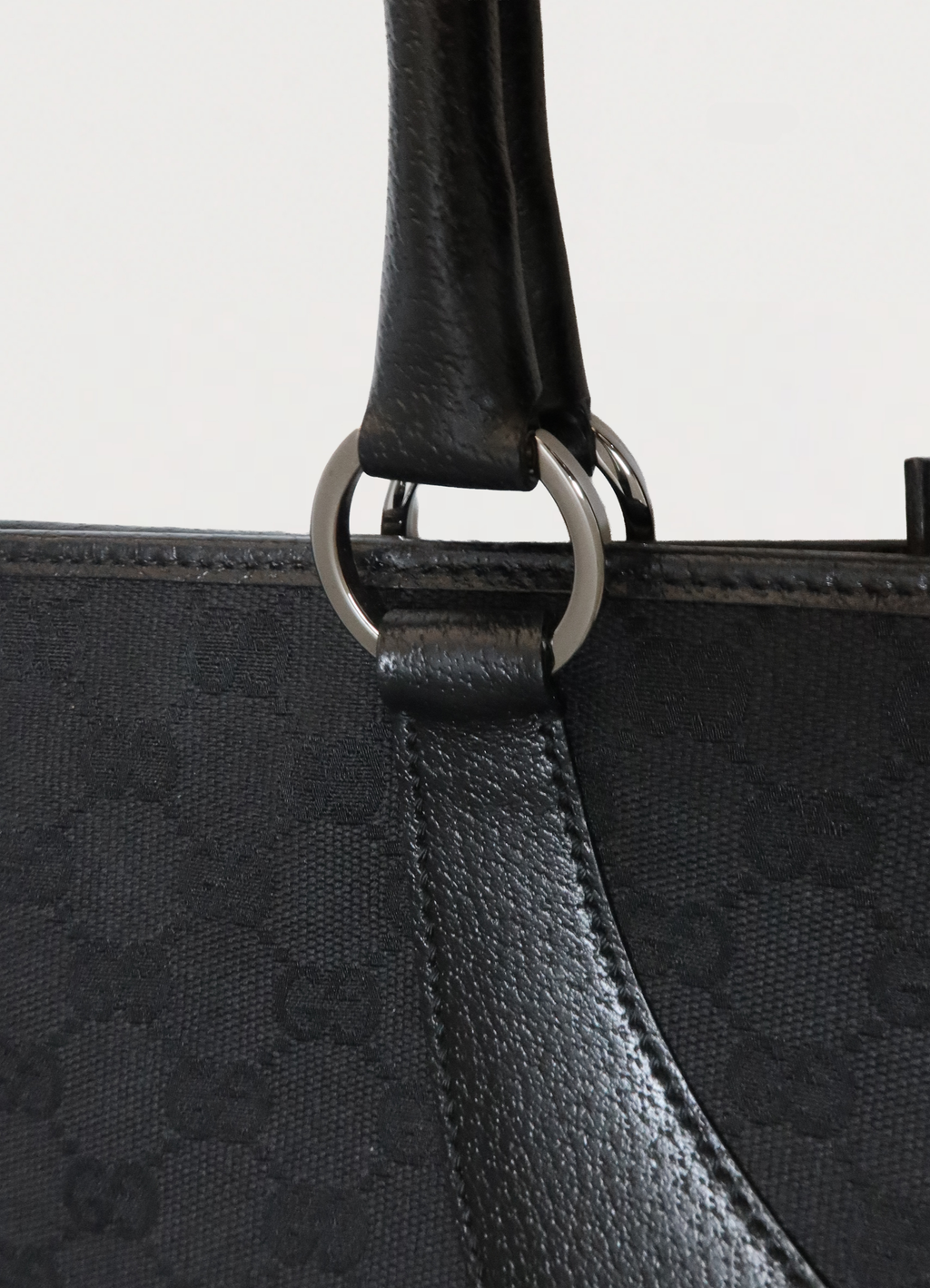 Close up of the gunmetal-tone rings and leather handle attachment on Gucci bag