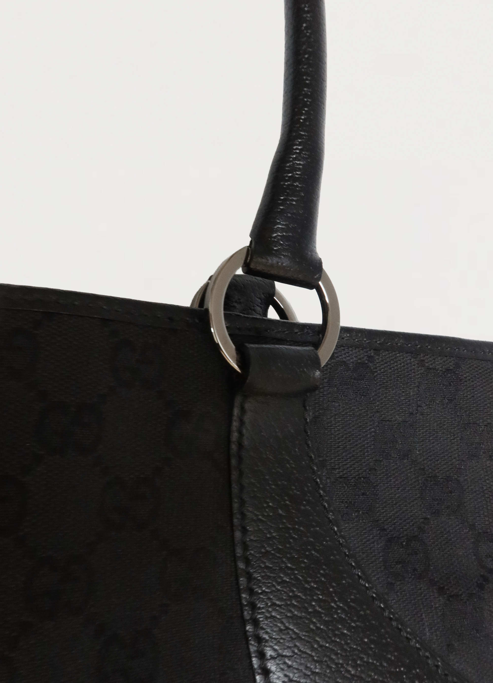 Close up of the gunmetal-tone rings and leather handle attachment on Gucci bag